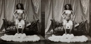 view A young woman, full-length, posed naked sitting on a table with her feet on a fur-covered stool, in a photographic studio. Photograph, ca.1900.