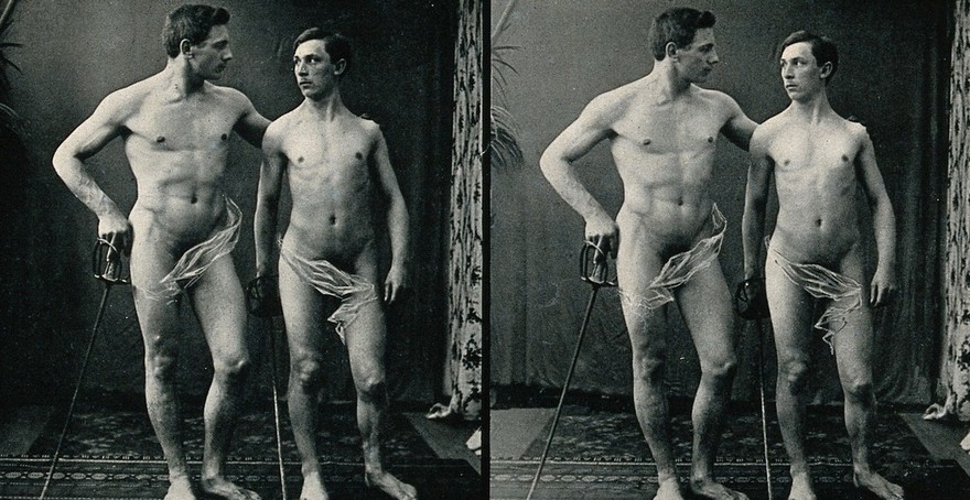 Two men posing naked in a photographic studio, standing with fencing epees. Stereo photograph, c.1900.