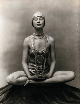 Marguerite Agniel posing with her legs crossed and hands together resting on her legs.