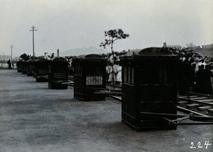 view A line of sedan chairs waiting beside a railway track, in Korea.