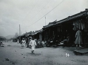 view A line of shops beside a dusty street, with telegraph poles overhead, in Korea.