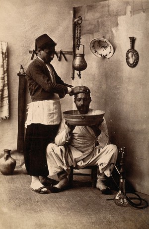 view North Africa: a man in a barber's shop having his hair washed. Photograph, ca. 1900 (?).