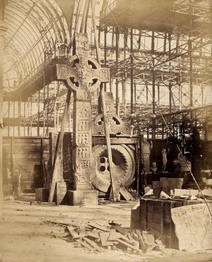 view The Crystal Palace during its re-erection at Sydenham, London: a large celtic cross and other statues in the unfinished interior. Photograph by Philip Delamotte, ca. 1854.