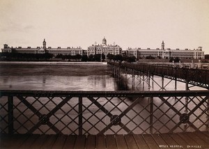 view Netley Hospital, Hampshire, England: exterior view showing soldiers on the bridge in the foreground. Photograph, ca. 1880 (?).