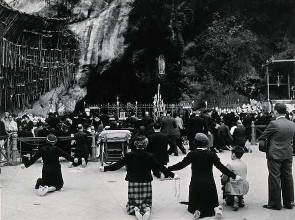 Lourdes, France: the grotto of Our Lady of Lourdes: pilgrims kneeling before the shrine. Photograph, ca. 1937.