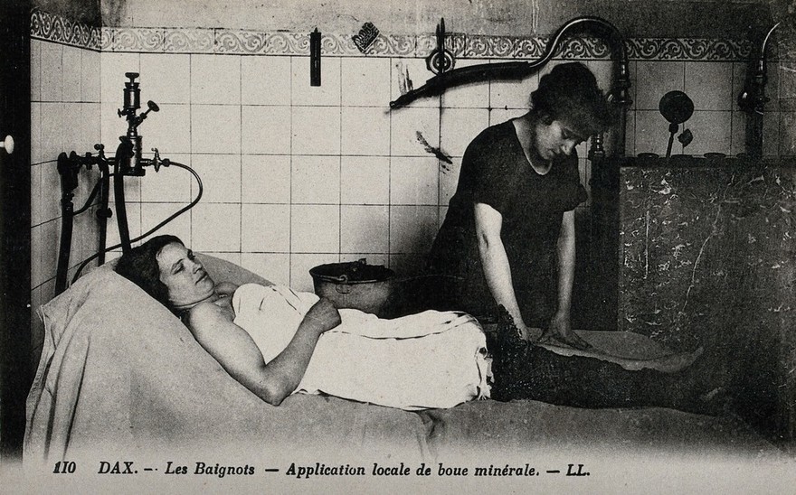 Dax, France: mud being applied on the leg of a patient of a thermal establishment. Photographic postcard, ca. 1920.