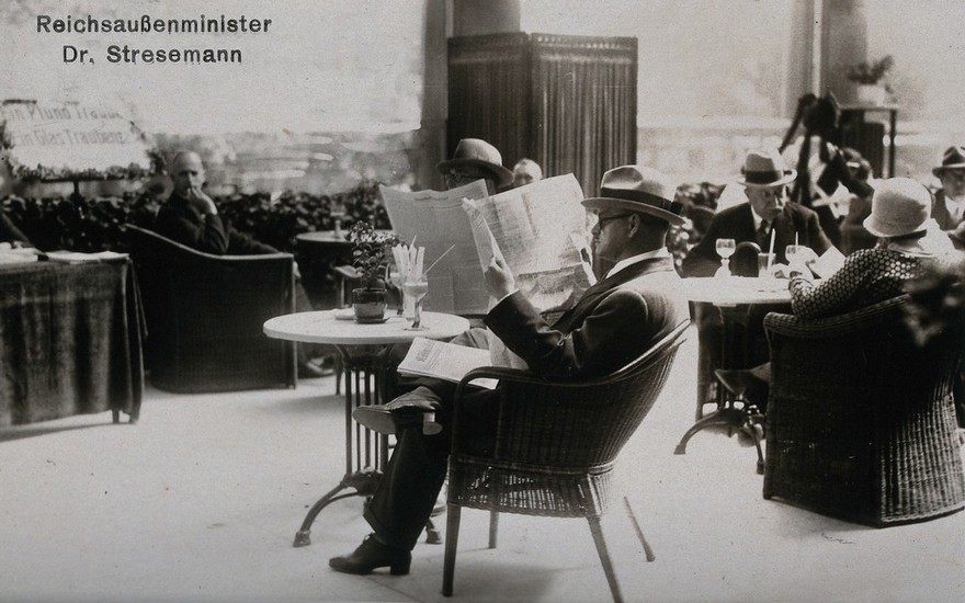 Baden-Baden, Germany: Gustav Stresemann sitting on the terrace of a grape-cure establishment, reading the newspapers. Photographic postcard, 192-.