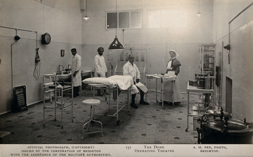 Two Indian doctors with a British doctor and a British nurse in the operating theatre of the Royal Pavilion, Brighton. Photographic postcard by A.H. Fry, ca. 1915.