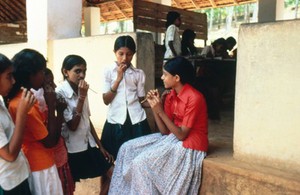 view Schoolgirls cleaning teeth with neem twigs in India