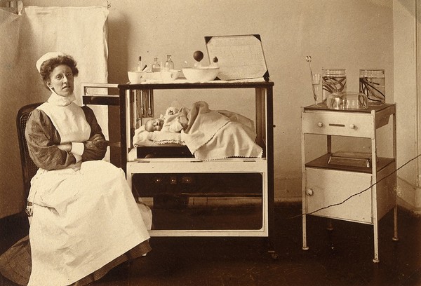 General Lying In Hospital, York Road, Lambeth: nurse sitting with baby in incubator. Photograph, 1908.