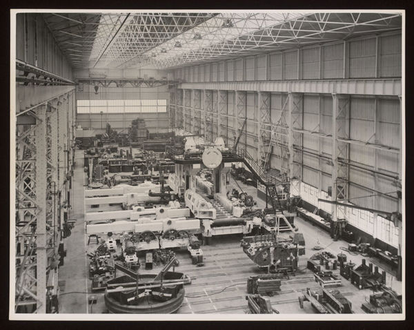 Heavy erecting shop, Davy & United Engineering Co. Ltd., Park Iron Works, Sheffield: a view of a large reversing blooming mill under construction, surrounded by machines and cranes. Photograph, 1957.