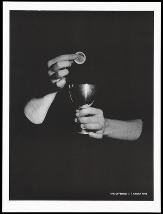 The arms of a man emerge from the darkness holding a silver communion cup into which a condom is about to be dropped; a safe-sex and AIDS prevention message. Lithograph by T. Kanar, 1993.