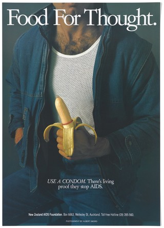 A man wearing a white vest and denim jacket holds a peeled banana with a condom representing an advertisement for safe sex by the New Zealand AIDS Foundation. Colour lithograph by Albert Sword.