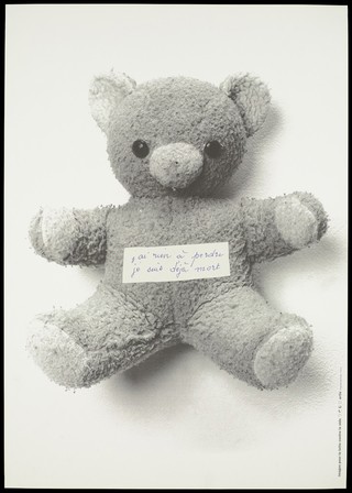 A worn teddy bear labelled in French 'I have nothing to lose, I am already dead'; representing child AIDS-patients (?). Silk screen print after C. Lévêque, 1993.
