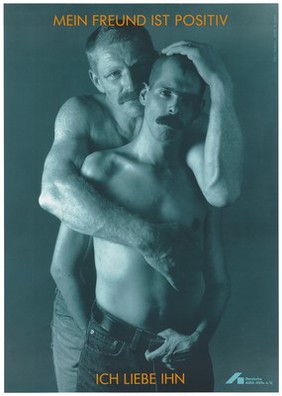 Two bare-chested men wearing jeans and moustaches hold each other with the message in German: "My friend is [HIV] positive. I love him"; an advertisement by the Deutsche AIDS-Hilfe e.V. Colour lithograph by I. Taubhorn and W. Mudra.