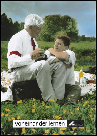 A boy learns from an older man about AIDS; an advertisement for AIDS education by the Deutsche AIDS-Hilfe e.V. Colour lithograph by Michael Taubenheim and Wolfgang Mudra.