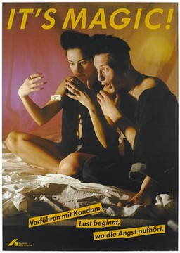 A woman and a man sit on a bed staring at a condom as if it floats magically mid-air; an advertisement for safe sex by the Deutsche AIDS-Hilfe e.V. Colour lithograph by R. Warzecha, M. Jahreiss and D. Pusch.