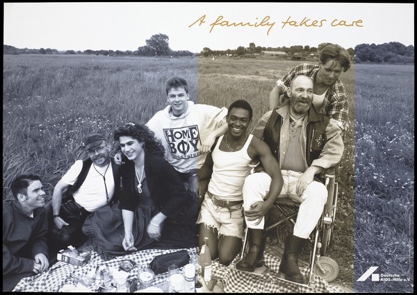 A group of gay men including a transvestite, a black man and a man in a wheelchair sit having a picnic on a check blanket in a field with the message: "A family takes care"; an advertisement for the support services for gay men affected by AIDS by the Deutsche AIDS-Hilfe e.V. Colour lithograph by Michael Taubenheim and Wolfgang Mudra.