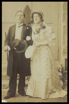 Two men, one in drag, dressed as bride and groom. Photographic postcard, 191-.