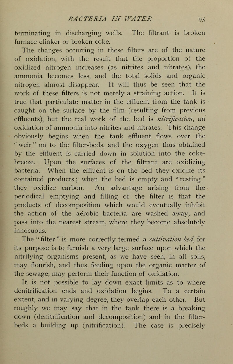 terminating in discharging wells. The filtrant is broken furnace clinker or broken coke. The changes occurring in these filters are of the nature of oxidation, with the result that the proportion of the oxidized nitrogen increases (as nitrites and nitrates), the ammonia becomes less, and the total solids and organic nitrogen almost disappear. It will thus be seen that the work of these filters is not merely a straining action. It is true that particulate matter in the effluent from the tank is caught on the surface by the film (resulting from previous effluents), but the real work of the bed is nitrification, an oxidation of ammonia into nitrites and nitrates. This change obviously begins when the tank effluent flows over the weir on to the filter-beds, and the oxygen thus obtained by the effluent is carried down in solution into the coke- breeze. Upon the surfaces of the filtrant are oxidizing bacteria. When the effluent is on the bed they oxidize its contained products ; when the bed is empty and  resting they oxidize carbon. An advantage arising from the periodical emptying and filling of the filter is that the products of decomposition which would eventually inhibit the action of the aerobic bacteria are washed away, and pass into the nearest stream, where they become absolutely innocuous. The  filter  is more correctly termed a cultivation bed, for its purpose is to furnish a very large surface upon which the nitrifying organisms present, as we have seen, in all soils, may flourish, and thus feeding upon the organic matter of the sewage, may perform their function of oxidation. It is not possible to lay down exact limits as to where denitrification ends and oxidation begins. To a certain extent, and in varying degree, they overlap each other. But roughly we may say that in the tank there is a breaking down (denitrification and decomposition) and in the filter- beds a building up (nitrification). The case is precisely