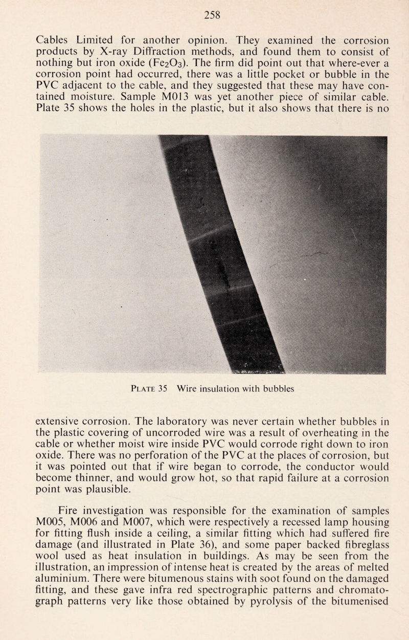 Cables Limited for another opinion. They examined the corrosion products by X-ray Diffraction methods, and found them to consist of nothing but iron oxide (Fe20s). The firm did point out that where-ever a corrosion point had occurred, there was a little pocket or bubble in the PVC adjacent to the cable, and they suggested that these may have con¬ tained moisture. Sample M013 was yet another piece of similar cable. Plate 35 shows the holes in the plastic, but it also shows that there is no Plate 35 Wire insulation with bubbles extensive corrosion. The laboratory was never certain whether bubbles in the plastic covering of uncorroded wire was a result of overheating in the cable or whether moist wire inside PVC would corrode right down to iron oxide. There was no perforation of the PVC at the places of corrosion, but it was pointed out that if wire began to corrode, the conductor would become thinner, and would grow hot, so that rapid failure at a corrosion point was plausible. Fire investigation was responsible for the examination of samples M005, M006 and M007, which were respectively a recessed lamp housing for fitting flush inside a ceiling, a similar fitting which had suffered fire damage (and illustrated in Plate 36), and some paper backed fibreglass wool used as heat insulation in buildings. As may be seen from the illustration, an impression of intense heat is created by the areas of melted aluminium. There were bitumenous stains with soot found on the damaged fitting, and these gave infra red spectrographic patterns and chromato¬ graph patterns very like those obtained by pyrolysis of the bitumenised