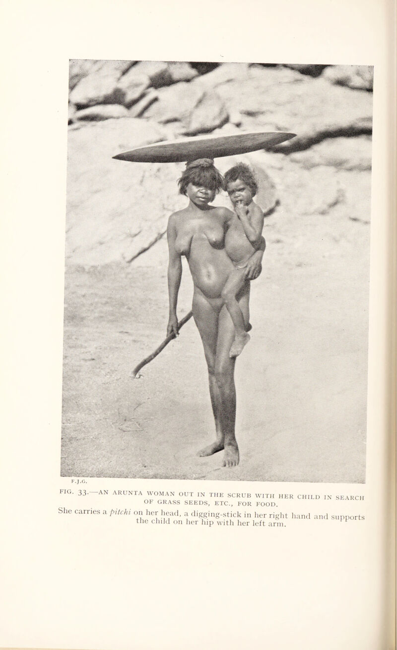 FIG. 33- -AN ARUNTA WOMAN OUT IN THE SCRUB WITH HER CHILD IN SEARCH OF GRASS SEEDS, ETC., FOR FOOD. She carries a pitchi on her head, a digging-stick in her right hand and supports