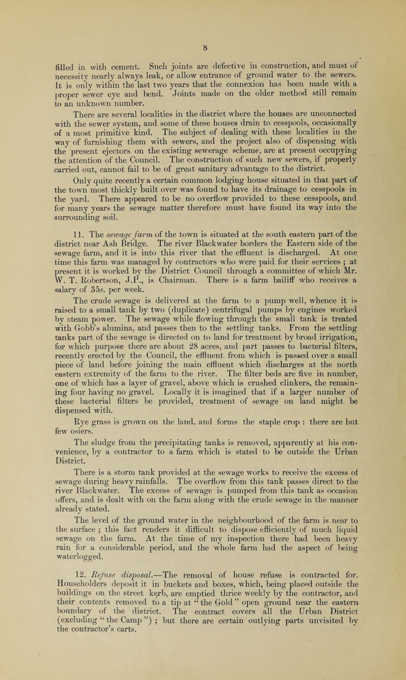 filled in with cement. Such joints are defective in construction, and must of necessity nearly always leak, or allow entrance of ground water to the sewers. It is only within the last two years that the connexion has been made with a proper sewer eye and bend. Joints made on the older method still remain to an unknown number. There are several localities in the district where the houses are unconnected with the sewer system, and some of these houses drain to cesspools, occasionally of a most primitive kind. The subject of dealing with these localities in the way of furnishing them with sewers, and the project also of dispensing with the present ejectors on the existing sewerage scheme, are at present occupying the attention of the Council. The construction of such new sewers, if properly carried out, cannot fail to be of great sanitary advantage to the district. Only quite recently a certain common lodging house situated in that part of the town most thickly built over was found to have its drainage to cesspools in the yard. There appeared to be no overflow provided to these cesspools, and for many years the sewage matter therefore must have found its way into the surrounding soil. 11. The sewage farm of the town is situated at the south eastern part of the district near Ash Bridge. The river Blackwater borders the Eastern side of the sewage farm, and it is into this river that the effluent is discharged. At one time this farm was managed by contractors who were paid for their services ; at present it is worked by the District Council through a committee of which Mr. W. T. Robertson, J.P., is Chairman. There is a farm bailiff who receives a salary of 35.s. per week. The crude sewage is delivered at the farm to a pump well, whence it is raised to a small tank by two (duplicate) centrifugal pumps by engines worked by steam power. The sewage while flowing through the small tank is treated with Cobb's alumina, and passes then to the settling tanks. From the settling tanks part of the sewage is directed on to land for treatment by broad irrigation, for which purpose there are about 28 acres, and part passes to bacterial filters, recently erected by the Council, the effluent from which is passed over a small piece of land before joining the main effluent which discharges at the north eastern extremity of the farm to the river. The filter beds are five in number, one of which has a layer of gravel, above which is crushed clinkers, the remain¬ ing four having no gravel. Locally it is imagined that if a larger number of these bacterial filters be provided, treatment of sewage on land might be dispensed with. Rye grass is grown on the land, and forms the staple crop : there are but few osiers. The sludge from the precipitating tanks is removed, apparently at his con¬ venience, by a contractor to a farm which is stated to be outside the Urban District. There is a storm tank provided at the sewage works to receive the excess of sewage during heavy rainfalls. The overflow from this tank passes direct to the river Blackwater. The excess of sewage is pumped from this tank as occasion offers, and is dealt with on the farm along with the crude sewage in the manner already stated. The level of the ground water in the neighbourhood of the farm is near to the surface ; this fact renders it difficult to dispose efficiently of much liquid sewage on the farm. At the time of my inspection there had been heavy rain for a considerable period, and the whole farm had the aspect of being waterlogged. 12. Refuse disposal.—The removal of house refuse is contracted for. Householders deposit it in buckets and boxes, which, being placed outside the buildings on the street kerb, are emptied thrice weekly by the contractor, and their contents removed to a tip at “the Gold” open ground near the eastern boundary of the district. The contract covers all the Urban District (excluding “ the Camp ”) ; but there are certain outlying parts unvisited by the contractor’s carts.