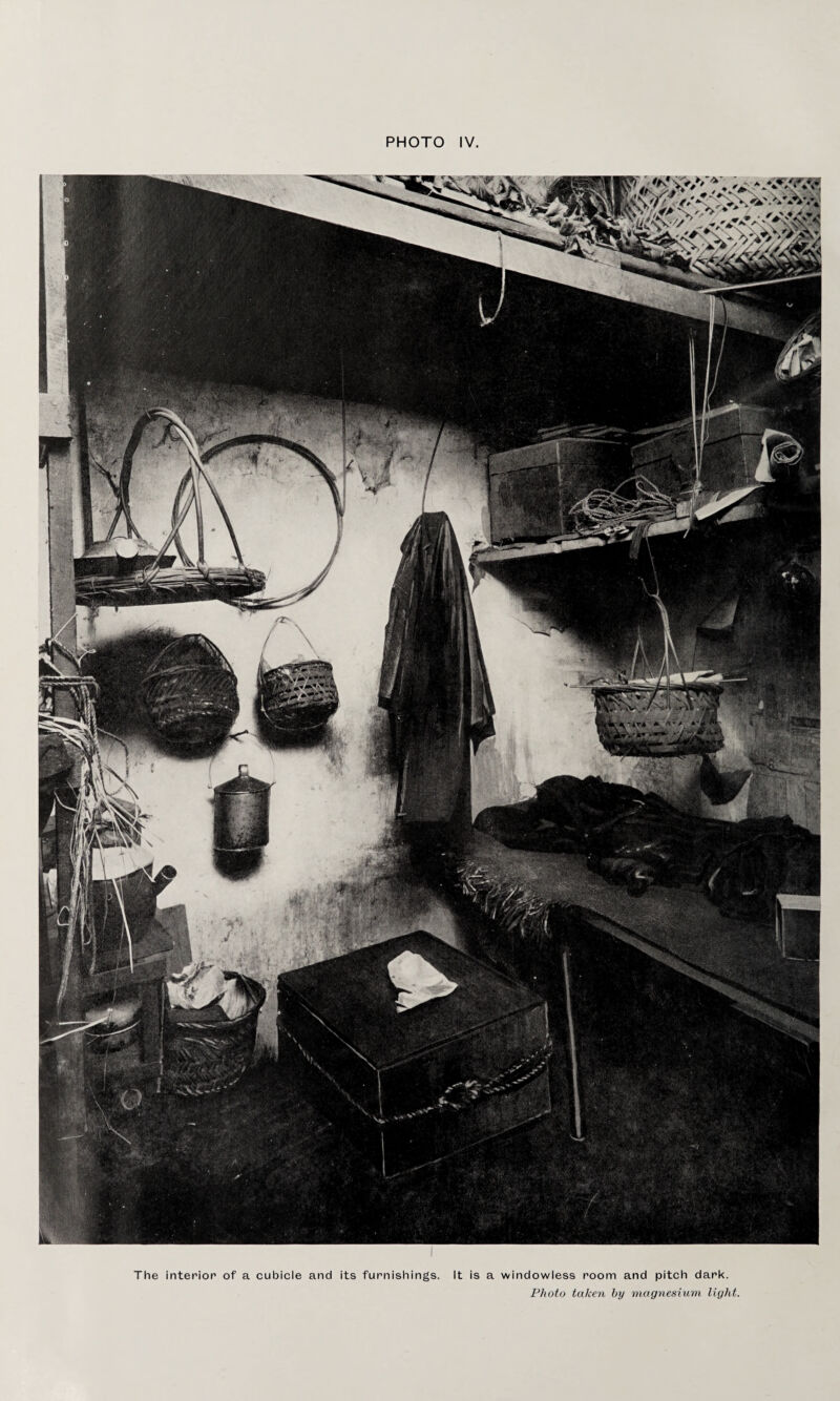 The interior of a cubicle and its furnishings. It is a windowless room and pitch dark. Photo taken by magnesium light.