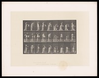 view A clothed woman combs her hair and washes her face, standing at a washstand. Collotype after Eadweard Muybridge, 1887.