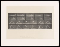 view A naked man lying down with raised left arm and head. A clothed man taps his knee. Collotype after Eadweard Muybridge, 1887.