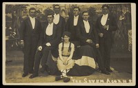 view Seven men on stage set of "The seven acorns". Photographic postcard, 1918-1920.