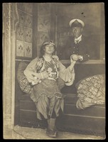 view A sailor holds hands with a man in elaborate drag. Photographic postcard, 191-.