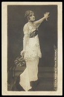 view A French prisoner of war acting in an internment camp in Dülmen, performing in drag, wearing a long white dress. Photographic postcard, 191-.