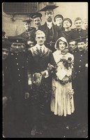 view Sailors on H.M.S Dominion, one in bridal drag, conduct a mock wedding on Christmas Day. Photographic postcard, 1915.