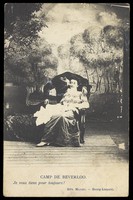 view Two amateur actors, one in drag, share a kiss on stage, in front of a detailed backdrop of trees at Beverloo Camp in Belgium. Process print, 190-.