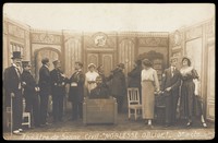 view Prisoners of war, some in drag, posing on stage during a crowded scene of "Noblesse oblige"; at Sennelager prisoner of war camp in Germany. Photographic postcard, 191-.