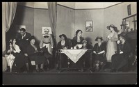 view Amateur actors, some in drag, are having tea on stage. Photographic postcard, 192-.