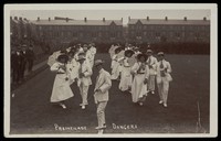 view A group of men, some in drag, dancing the Promenade on a lawn.