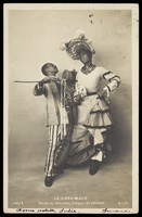 view Two black actors, Gregory and Brown, one in drag, dancing the Cake-Walk in Paris. Photographic postcard, 1903.