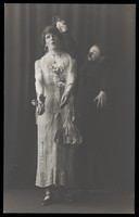 view Ralph Mellor in drag and another actor perform a scene in Trilby. Photographic postcard by L.S. Langfier, 192-.