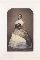 view A man in drag poses wearing an elaborate dress. Coloured photograph, 189-.