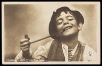 view Photograph of a boy in costume smoking a long pipe.