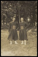 view Two men standing side by side in the woods. Photographic postcard, ca. 1910.