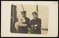 view Two naval officers posing with a dog. Photographic postcard, 192-.