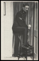 view A Royal Fusilier places one foot on a chair to display his boots, ca. 192-. Photograph, 195-.