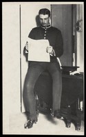 view A Royal Fusilier seated reading a newspaper in a domestic setting, ca. 192-. Photograph, 195-.