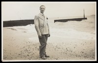 view A man posing on a beach in formal attire. Photographic postcard by Jerome Ltd., 192-.