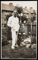 view A man poses wearing a white suit in a garden. Photographic postcard by Jerome Ltd., 192-.