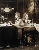 view Daisy and Violet Hilton, conjoined twins, one sewing, one using a typewriter. Photograph, c. 1927.