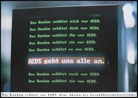 view A computer display screen bearing the words in German "The condom protects me ... you ... him ... them from AIDS" in green and in capitals against red the words: "AIDS affects us all"; an advertisement for condoms as a protection against AIDS by the German Ministry of Health. Colour lithograph by Marat.